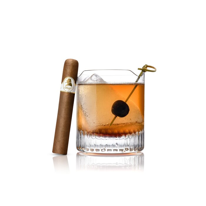 An herbal refresh Cocktail served in a Winston Churchill glass, with an Davidoff Winston Churchill Robusto cigar elegantly leaning against the glass, highlighting a refined pairing of drink and luxury cigar.