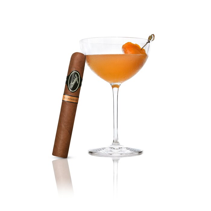 An Sweet and Spice Cocktail served in a Winston Churchill glass, with an Davidoff Nicaragua Toro cigar elegantly leaning against the glass, highlighting a refined pairing of drink and luxury cigar.