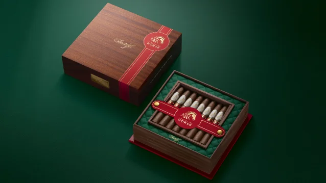 A luxurious wooden Davidoff Year of the Horse cigar box with a red ribbon featuring a horse design, revealing elegantly wrapped cigars inside a green velvet lining.
