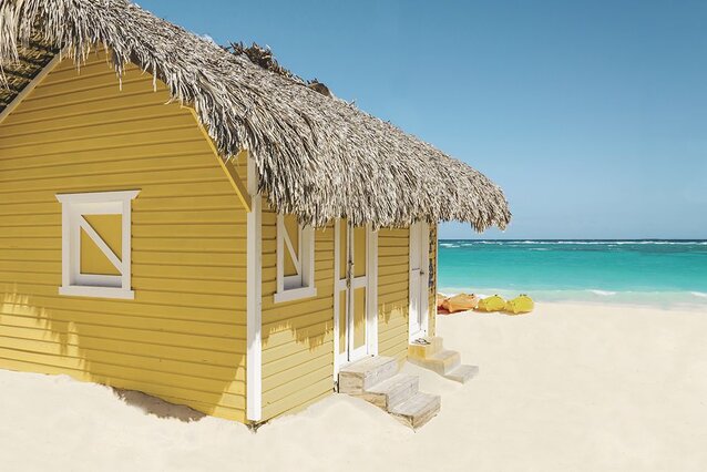 Yellow Beach house on the left with an sand beach and ocean view on the right.