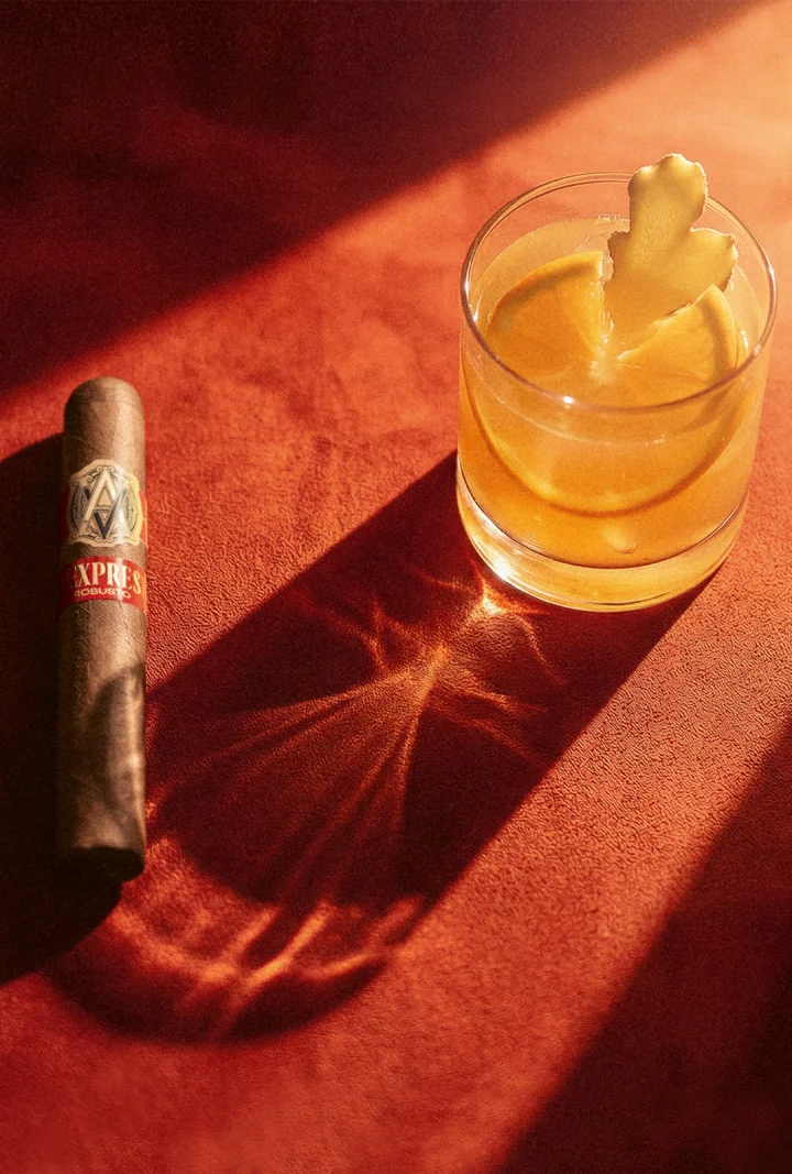 EXPRESIVO cigar next to a glass with a citrus ginger mocktail.