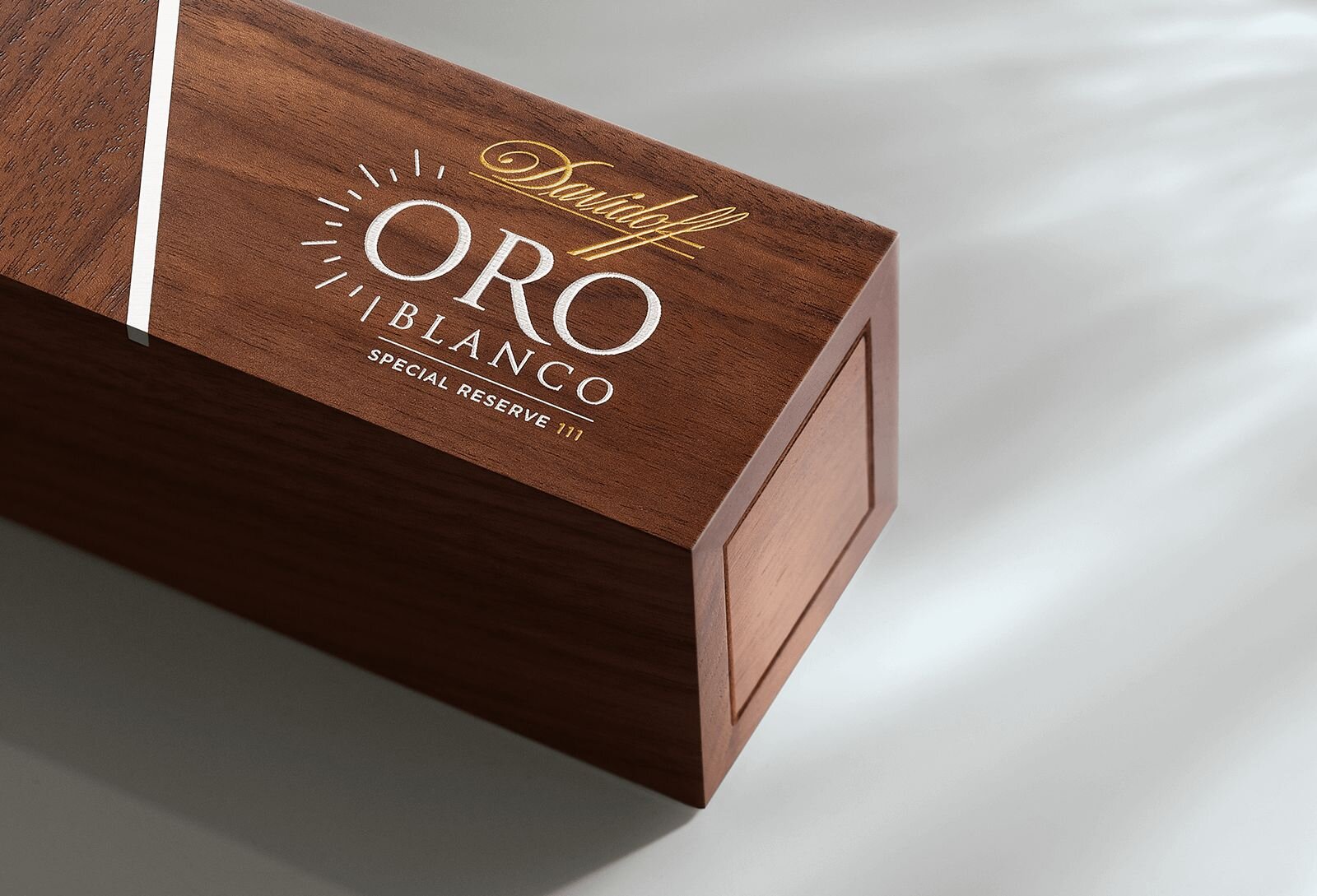 A close-up of the ‘Oro Blanco Special Reserve 111 Years’ cigar, elegantly displayed on a cigar box made of high-quality wood. 