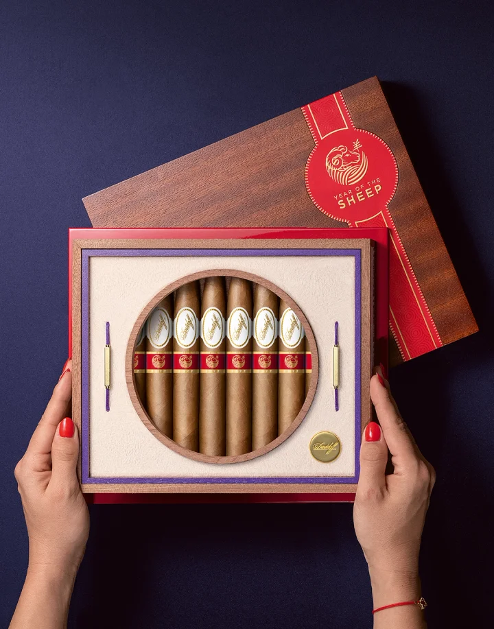 Two hands with red-painted nails that hold the opened box of the Year of the Sheep Limited Edition.
