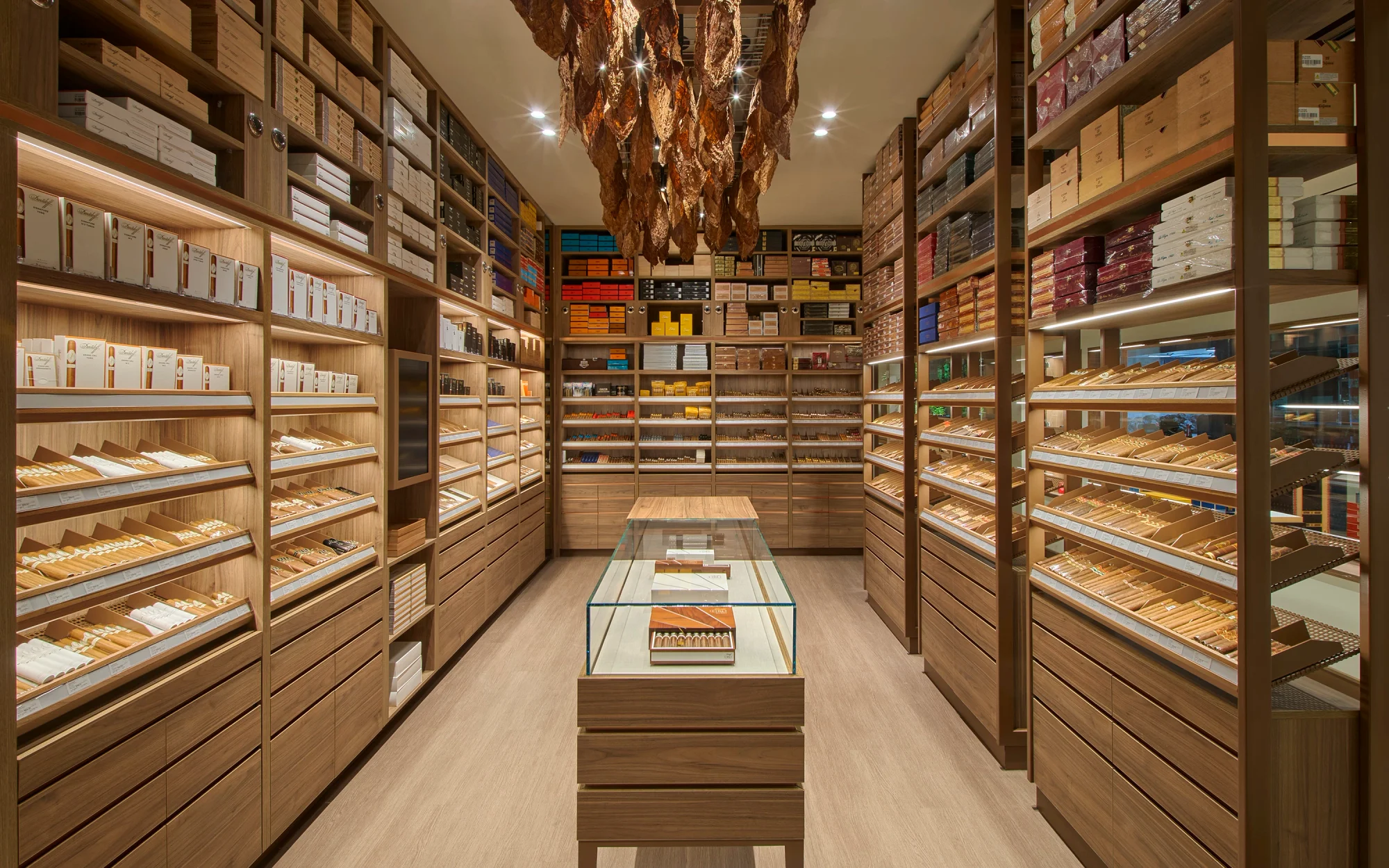 Modern retail space with wooden finishes, featuring display shelves, a circular counter, and a glass-walled product area.