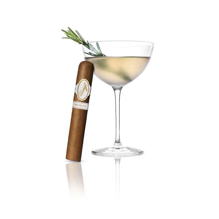 An Rosemary Wine Cocktail served in a Winston Churchill glass, with an Davidoff Grand Cru Robusto cigar elegantly leaning against the glass, highlighting a refined pairing of drink and luxury cigar.