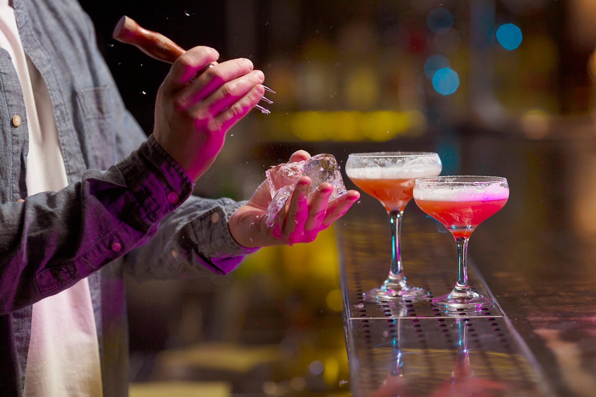 A close-up of a barman's hands and the cocktail mixing process