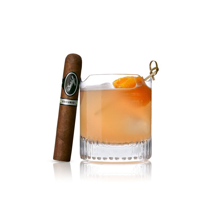 An Agave Green Cocktail served in a Winston Churchill glass, with an Aniversario No. 3 cigar elegantly leaning against the glass, highlighting a refined pairing of drink and luxury cigar.