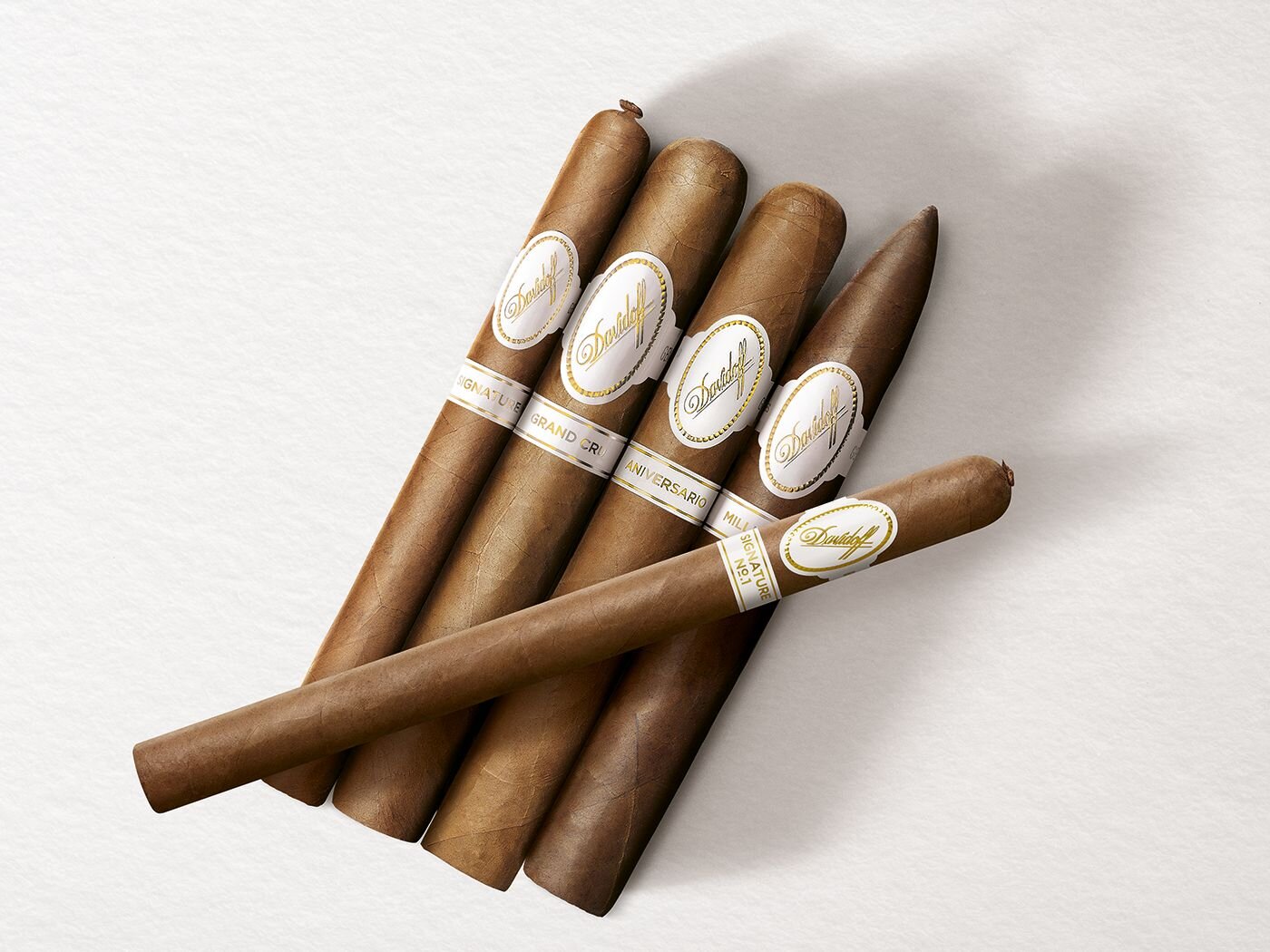 Four Davidoff cigars placed next to one another: Signature, Grand Cru, Aniversario and Millennium. Diagonally top of them lies a Davidoff Signature No. 1 Limited Edition Collection cigar. 