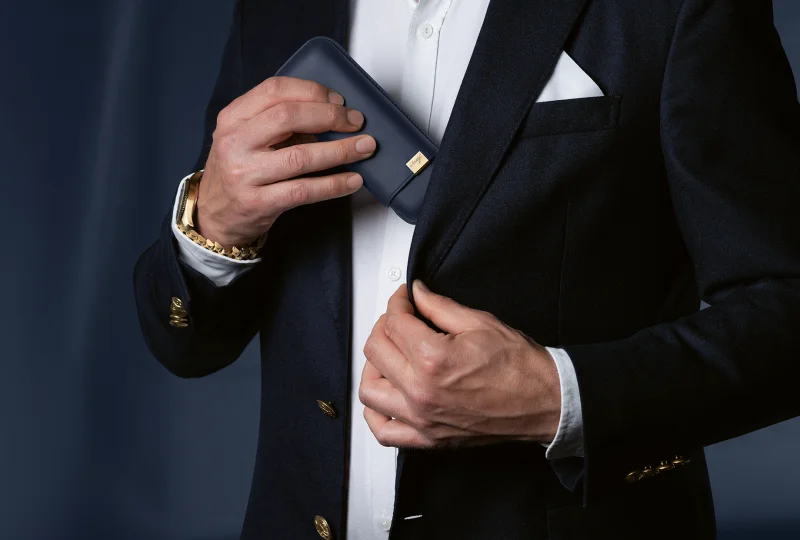 A man putting a blue Davidoff Cigar Case in his suit jacket.