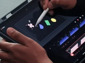 A person drawing on a tablet screen, focused on their artwork with a stylus in hand.