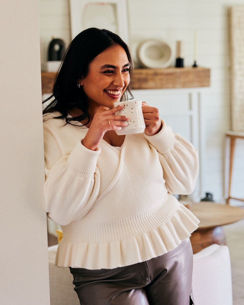 woman smiling in a dining room, holding a cup of coffee