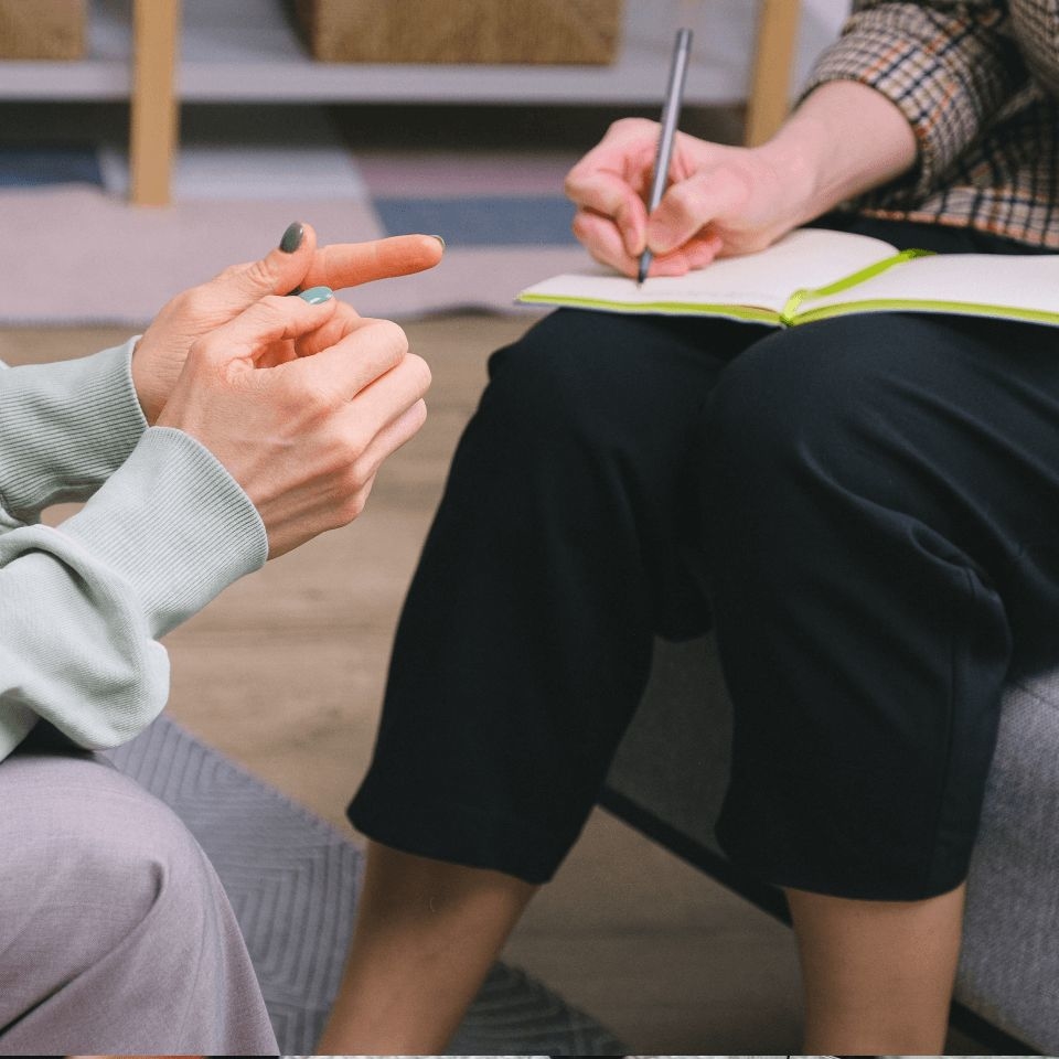 A female therapist takes notes before recommending a coping skills worksheet to her client