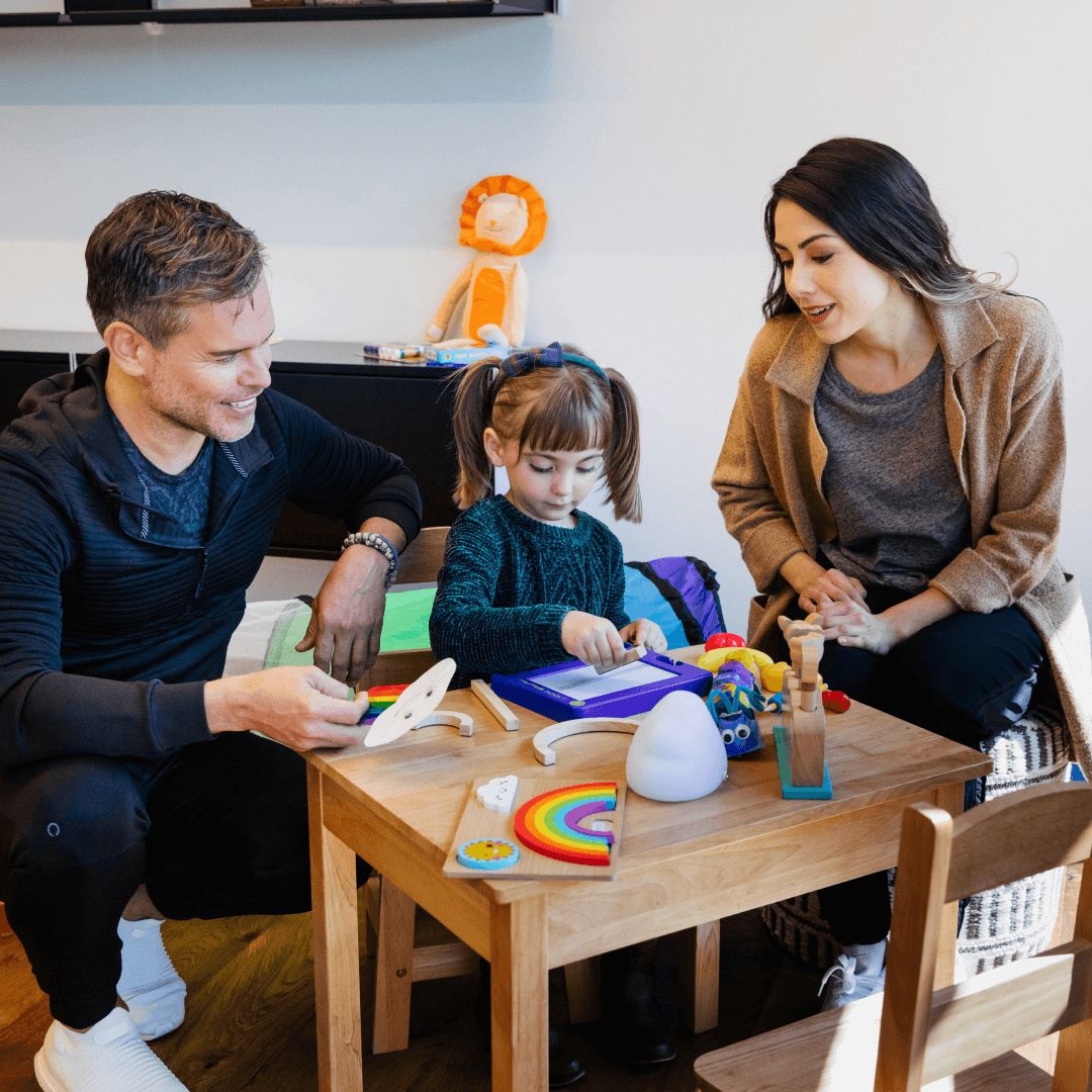 A mother and father sit at table with their daughter and complete pediatric occupational therapy assessments