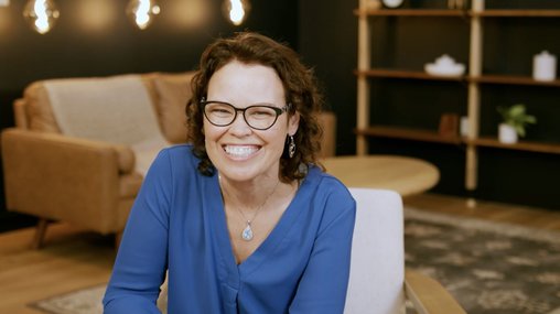 woman wearing glasses and smiling in a chair for an interview