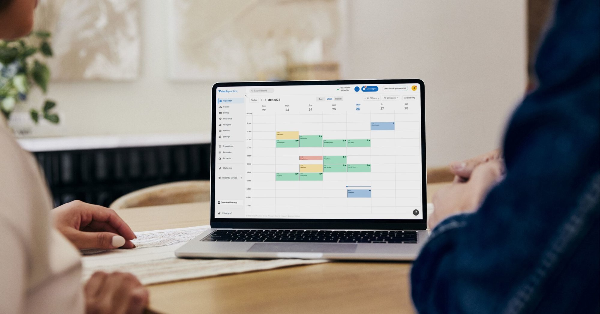 Clinicians looking at a laptop that is open to the calendar on SimplePractice