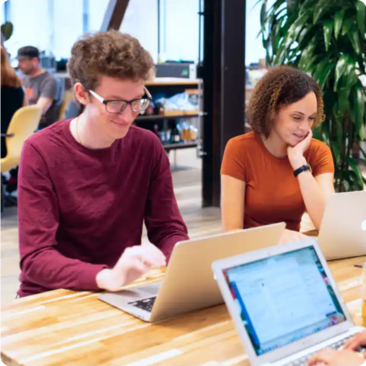 two simplepractice team members working together at a desk on laptops