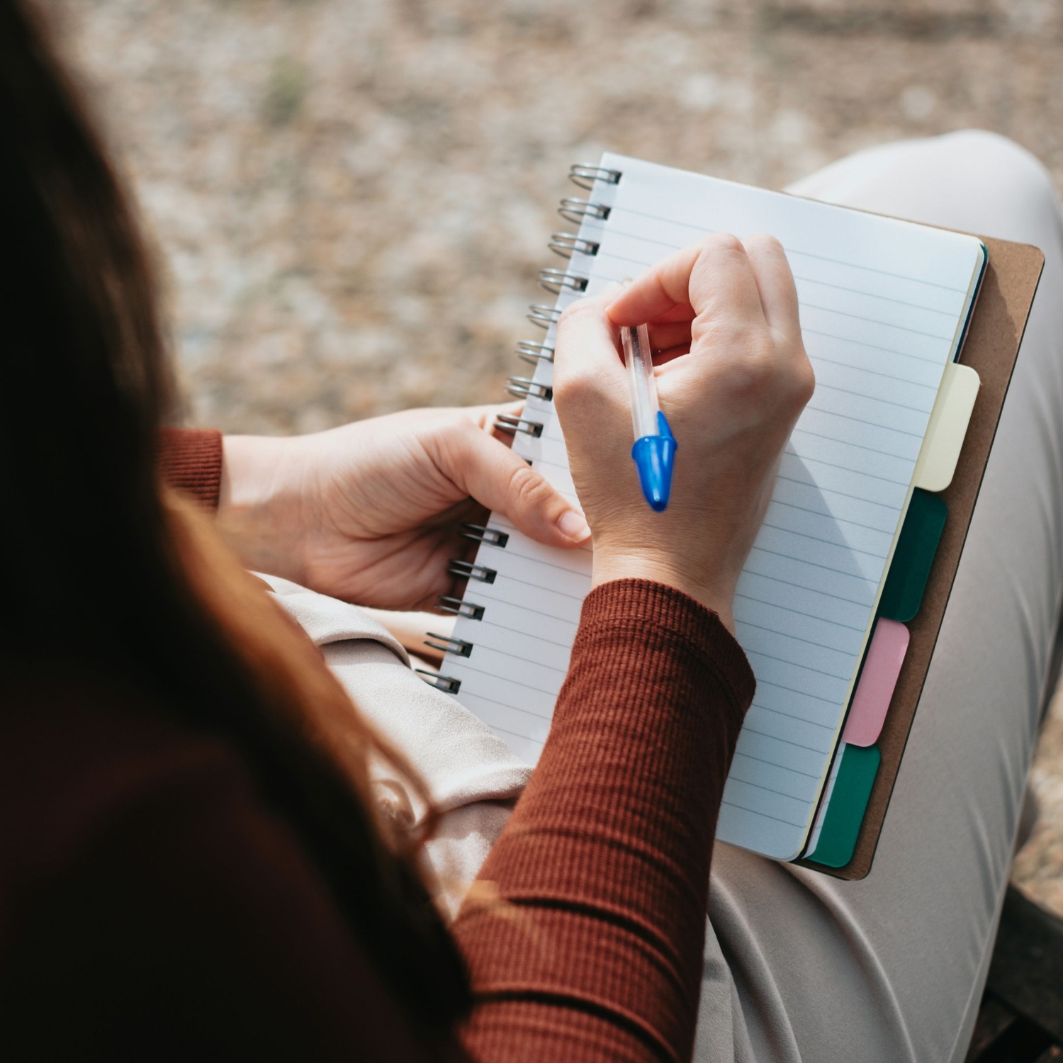 person writing cbt thought record in notebook