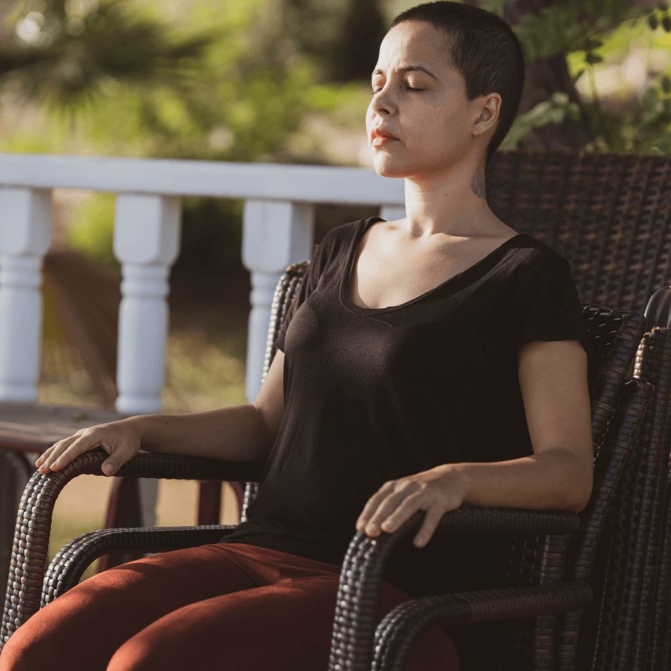 Woman sitting in a chair meditating after using our coping skills worksheets