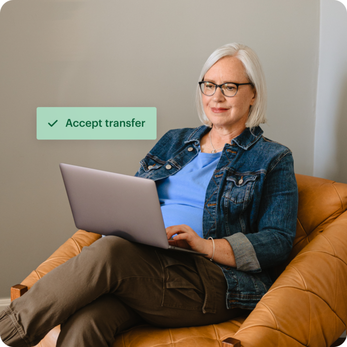 woman using laptop with graphic saying "Accept transfer" superimposed
