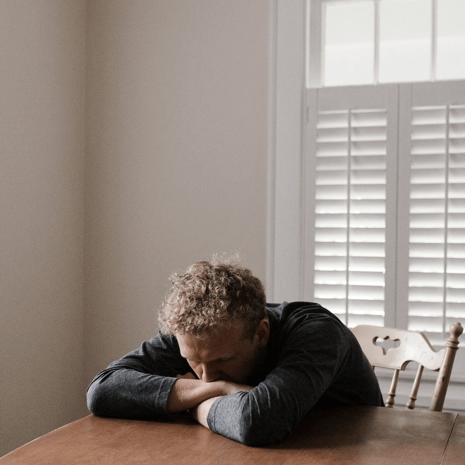 Depressed therapy client, showing signs of major depressive disorder codes, sits at a kitchen table