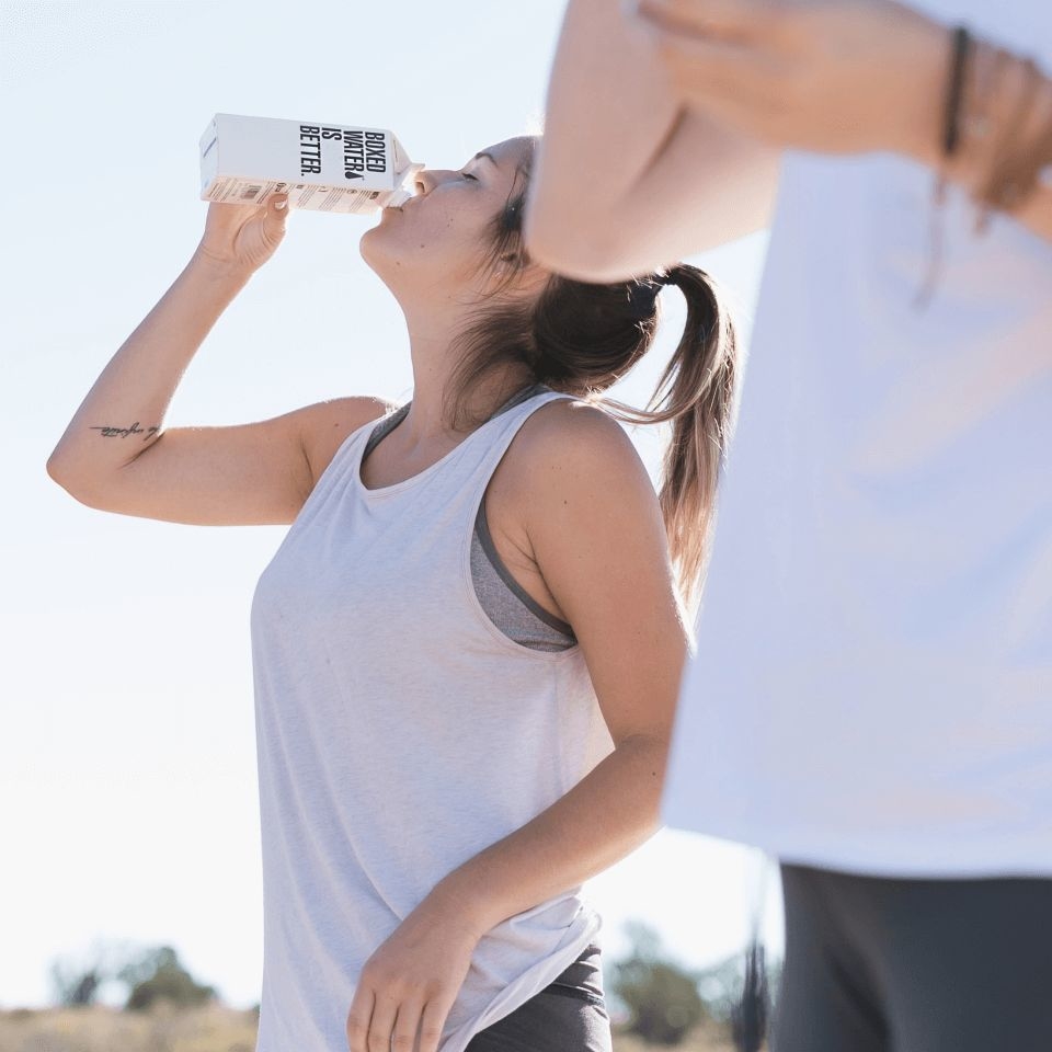 Woman drinking water while exercising outside in an act of self-care