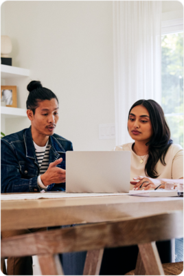 two clinicians sitting at a table looking at a laptop