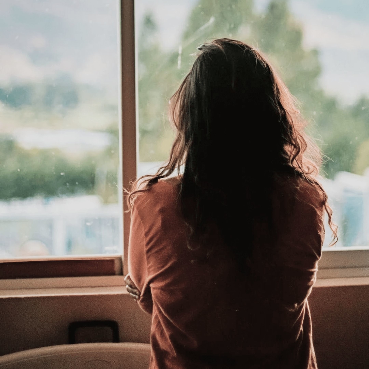 Female therapy client looking out window while feeling anxious