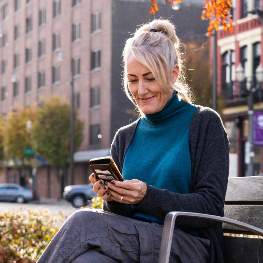 Female clinician looks at SOAP note examples on her phone while sitting outside