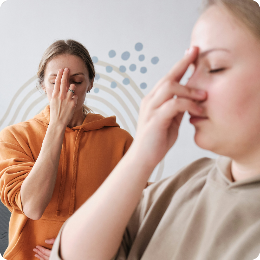 two people doing breathing exercises with their hands on their faces