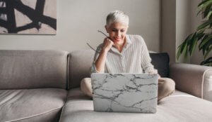 clinician sitting on a couch and looking at their laptop