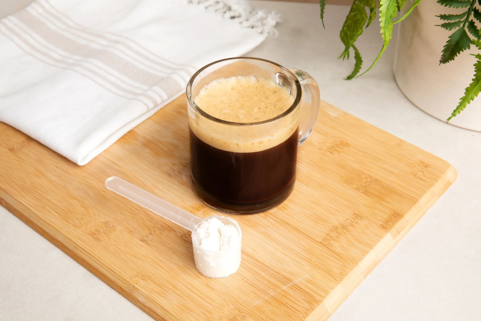 Cup of coffee with a scoop of NativePath Grass-Fed Collagen Peptides next to cup.