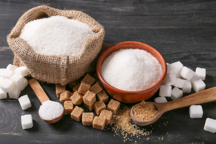 Sugar and brown sugar cubes on a dark table.