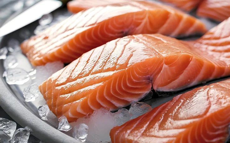 A close up photos of salmon fillets on a bed of ice