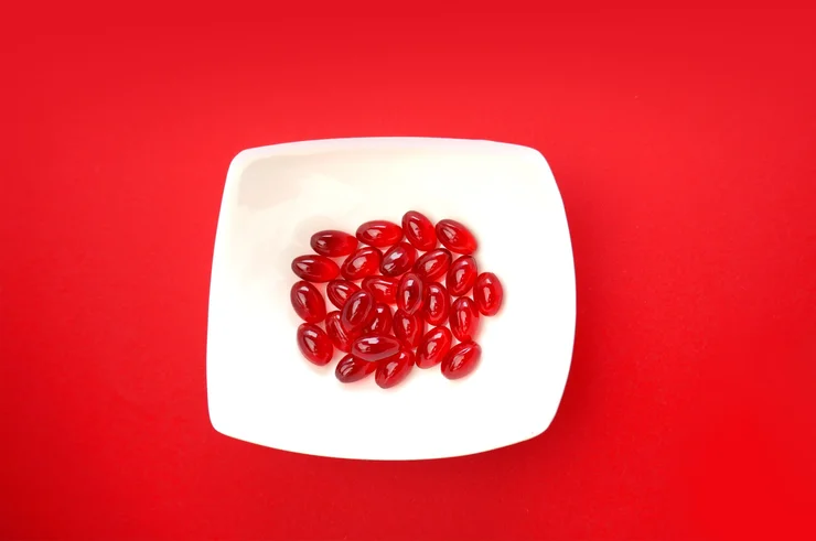 Krill oil soft gels on a white plate with a red background