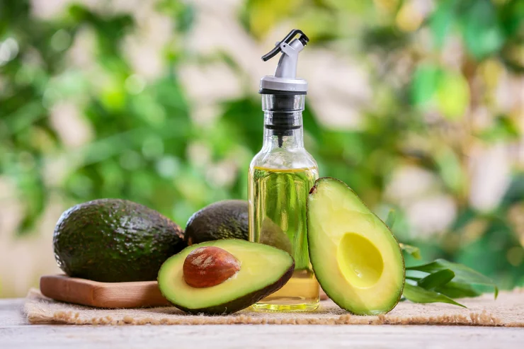 A bottle of avocado oil surrounded by avocados