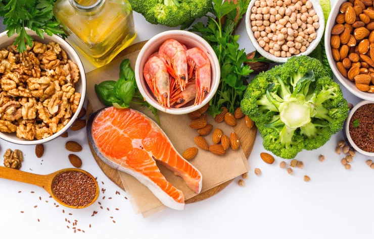 Top-view shot of foods high in omega-3s: walnuts, salmon, flax seeds, shellfish, olive oil.
