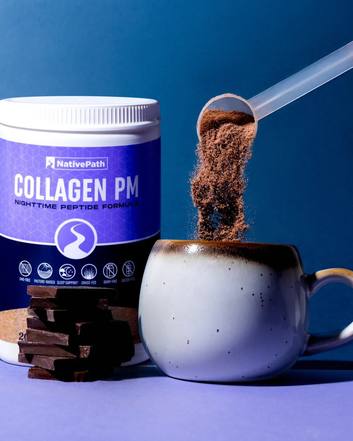 Scoop of Chocolate Collagen PM being poured into a ceramic mug. 