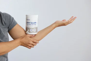 A container of NativePath Joint Health Collagen on a man's bent elbow