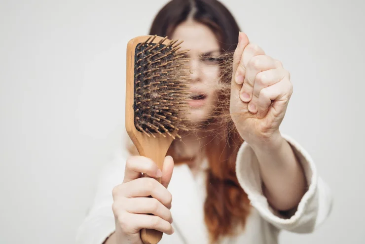 Brunette woman on a white background with a brush full of hair