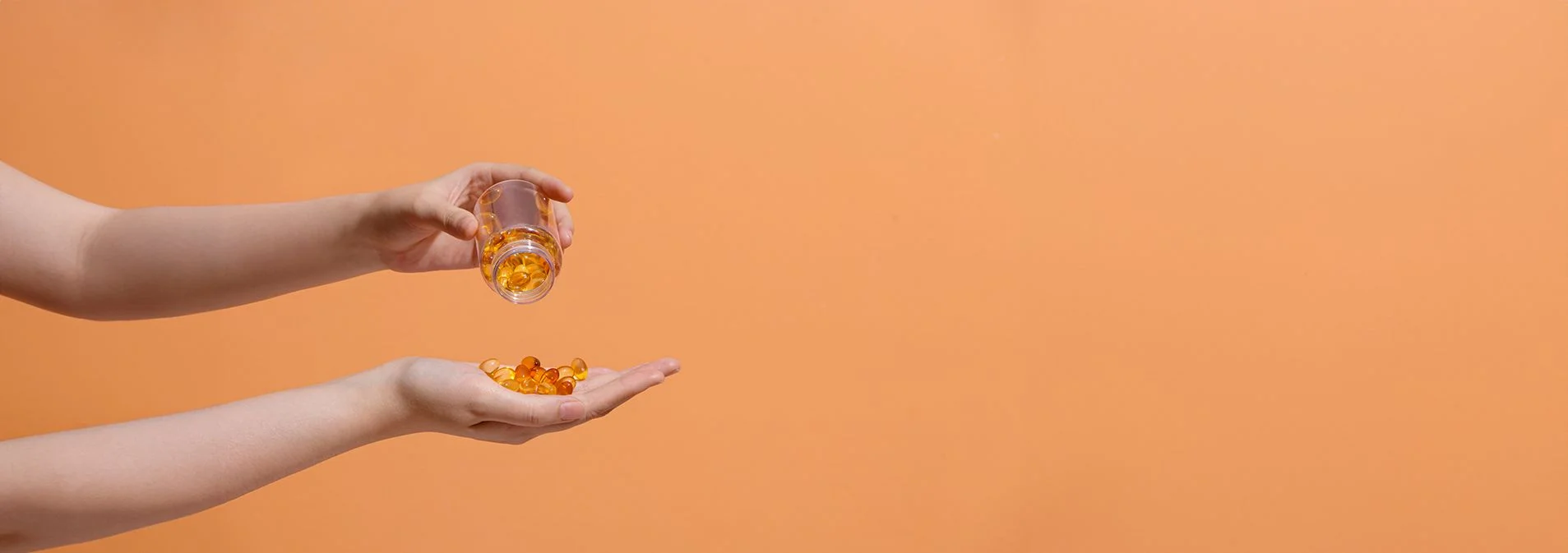 An outstretched hand pouring supplements into their other hand with an orange background
