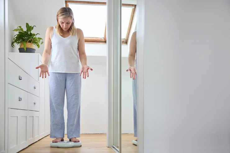 A woman confused and frustrated while stepping on a scale