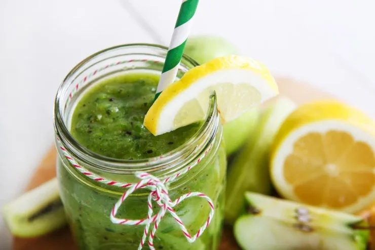 Collagen Detox Smoothie in a clear mason jar with lemon and apple slices surrounding it