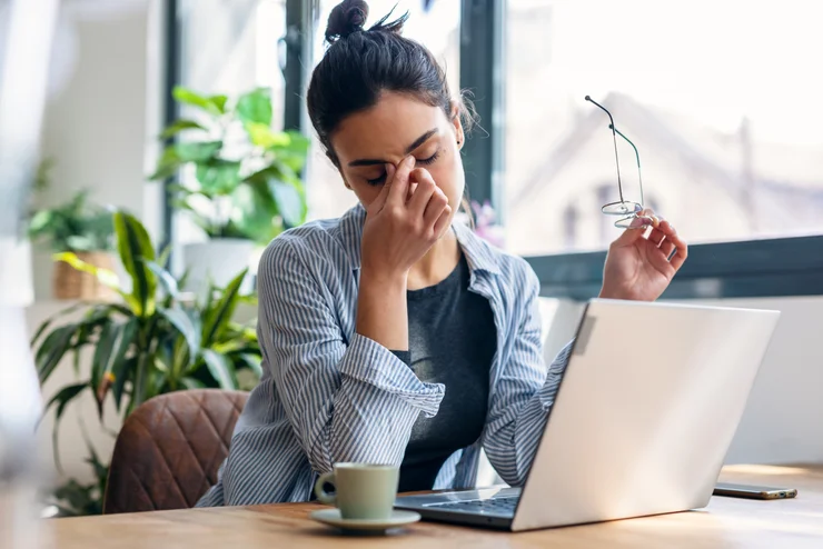 A woman working and very visibly tired from not getting enough sleep.