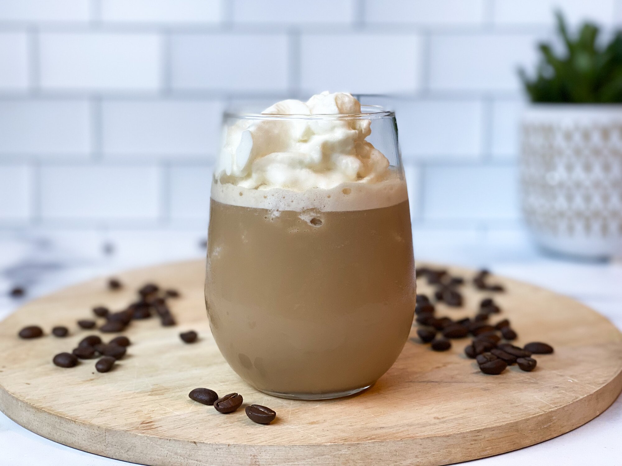 A close up shot of the Blended Vanilla Frappuccino on a wooden board with coffee beans in the background