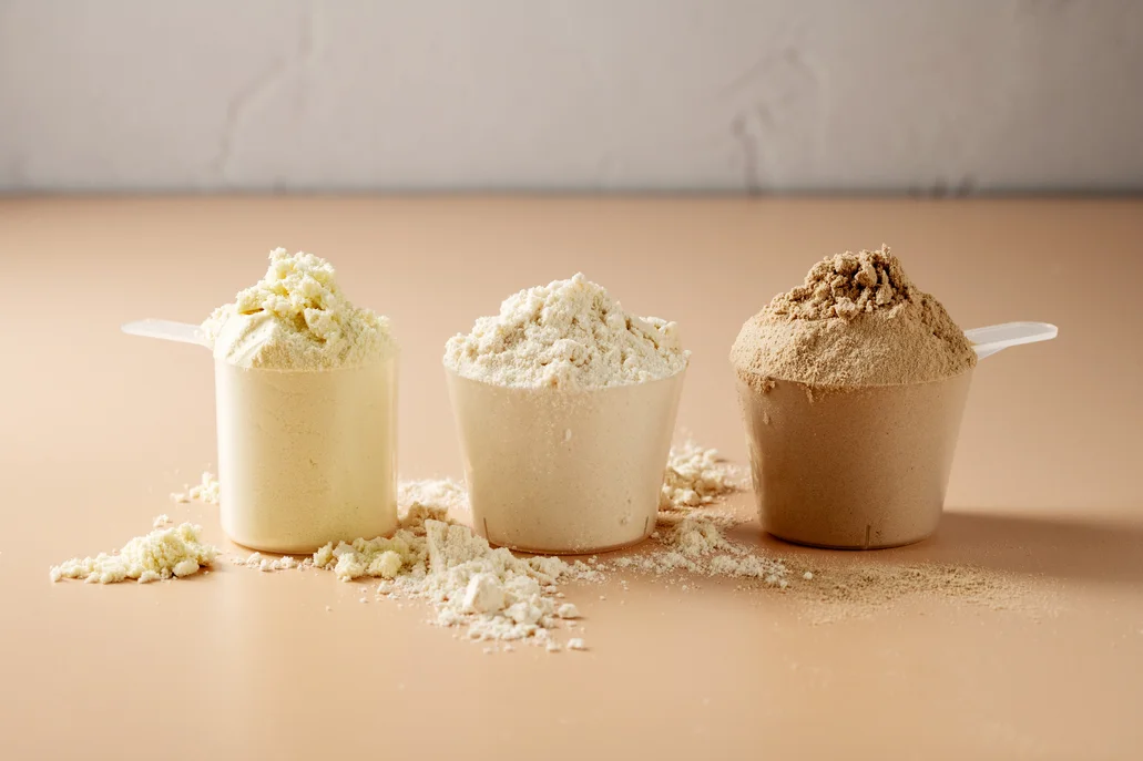 Three different flavor scoops of beef isolate protein powder on a beige background