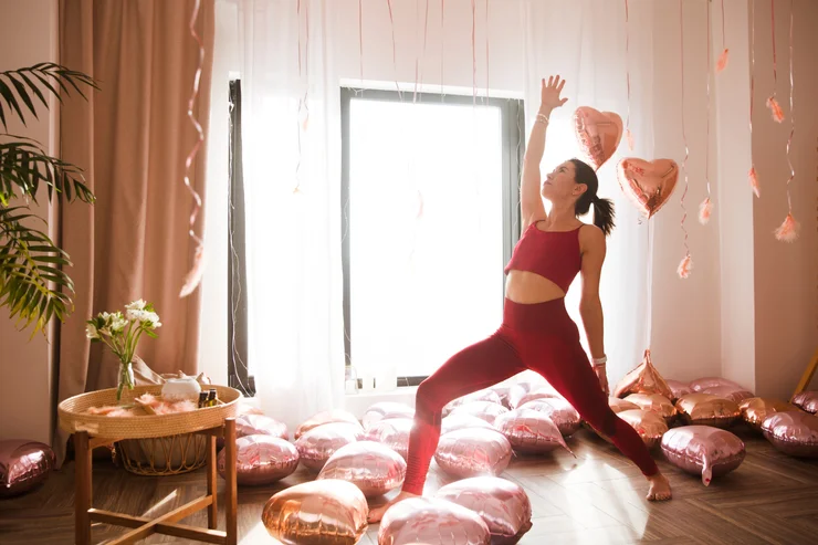 A woman practicing yoga surrounded by heart balloons as an act of self-love