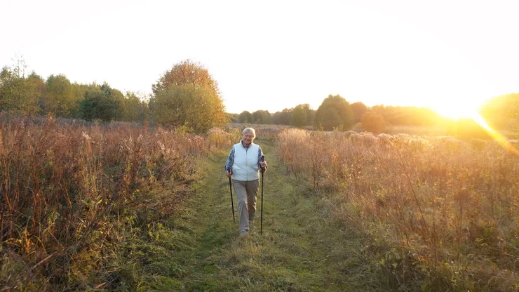 An older woman walking outdoors in nature for heart health.