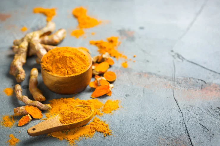 Raw organic orange turmeric root and powder, Curcuma longa on a table.