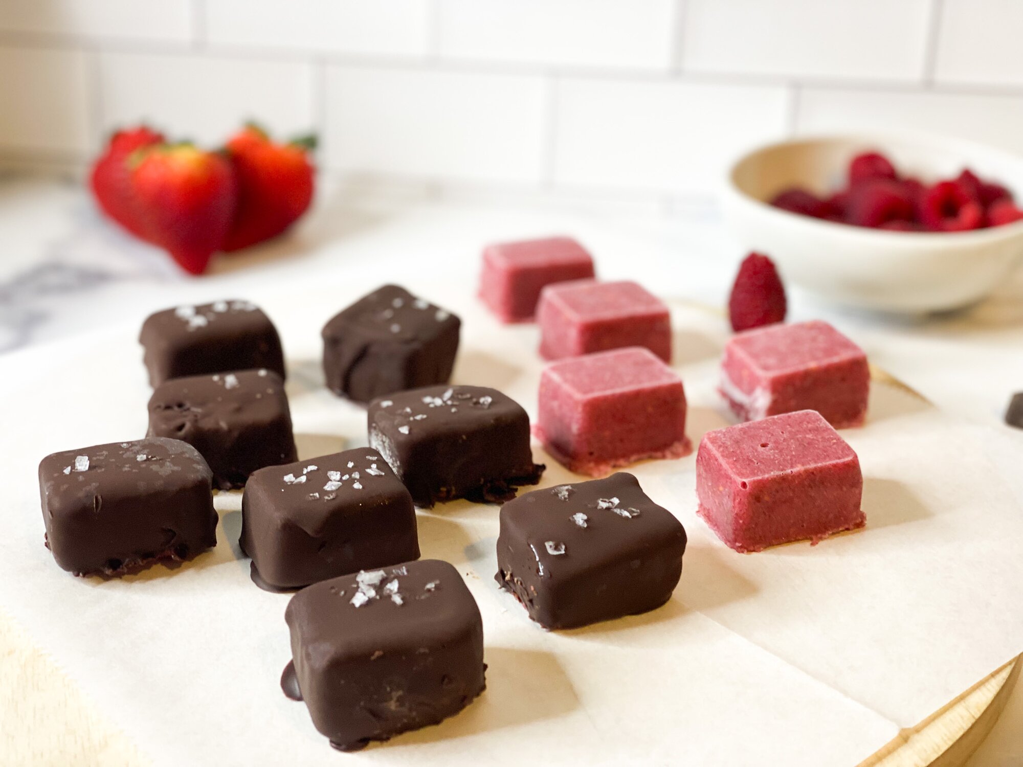 Berry Collagen bites on a wooden board, half covered in chocolate, half plain