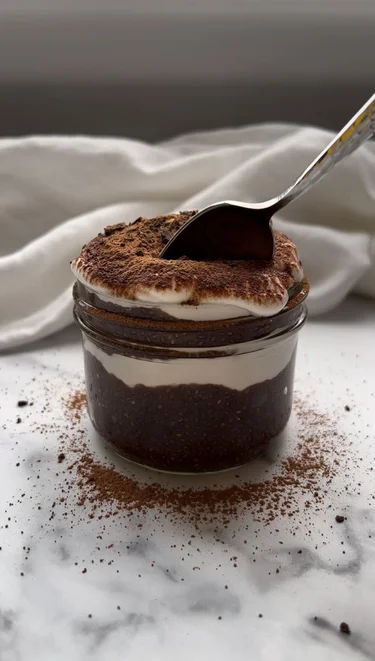 Tiramisu Chia Collagen Pudding in a small mason jar with a spoon sticking out of it